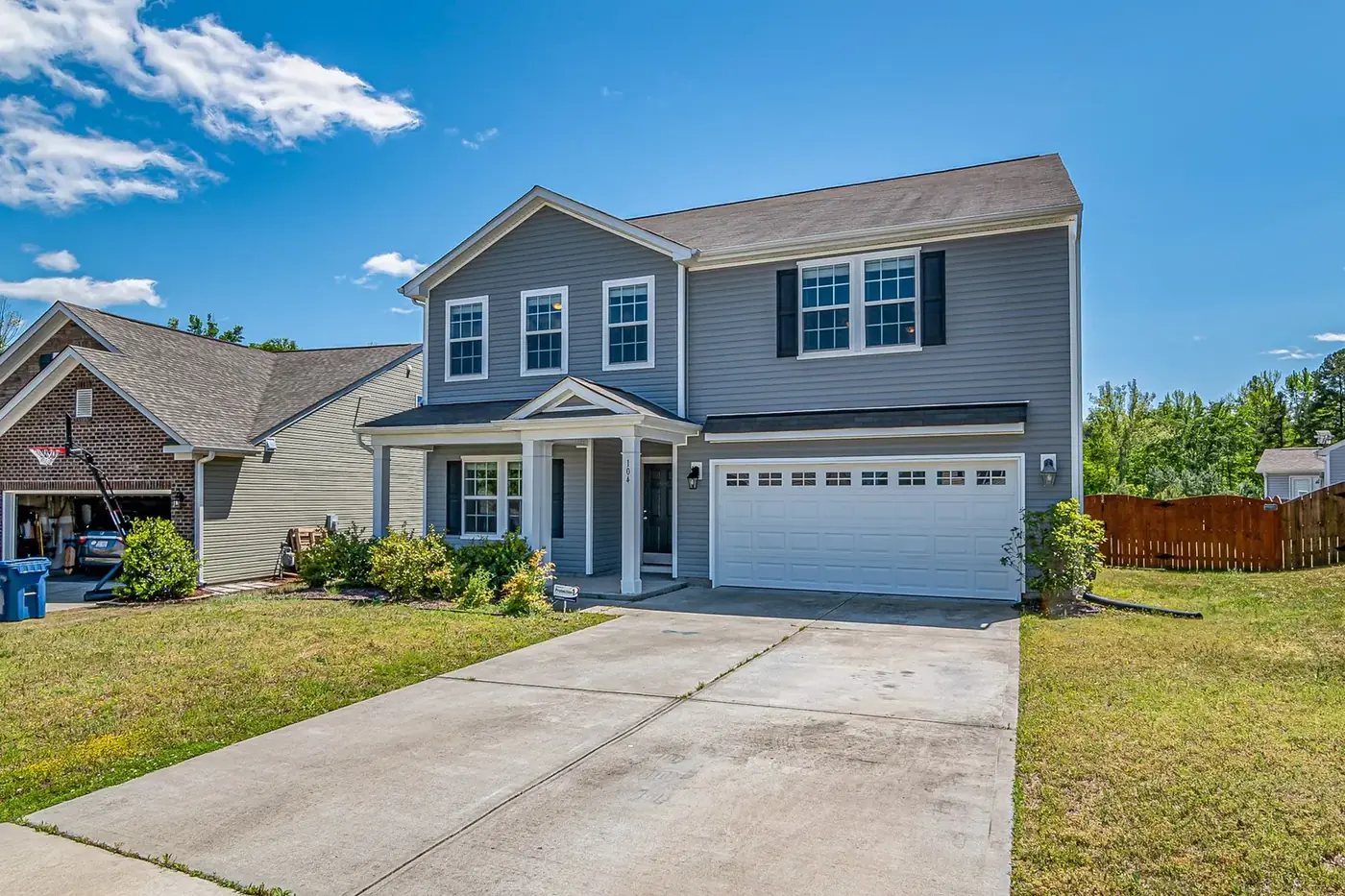 Gray two-story house with a broom-finish concrete driveway and front walkway